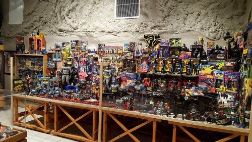 A display of various action figures and toys, featuring superheroes and vehicles, in a themed exhibit.