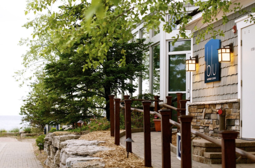 A scenic view of a restaurant entrance surrounded by greenery and stone pathways, with a sign reading "blu."