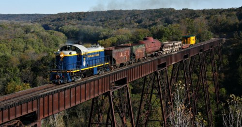 a train with the Boone & Scenic Valley Railroad in Iowa traveling over a railroad bridge over a river