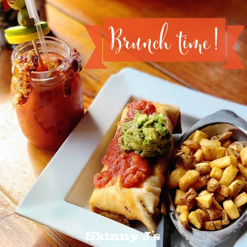 A delicious brunch spread featuring a burrito topped with guacamole and salsa, alongside crispy potatoes and a drink.