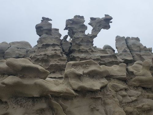 Unique rock formations with intricate textures and shapes against a cloudy sky.