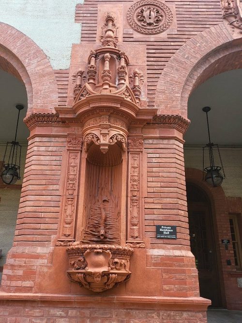 Intricate red brick architectural detail featuring ornate carvings and a central water fountain.