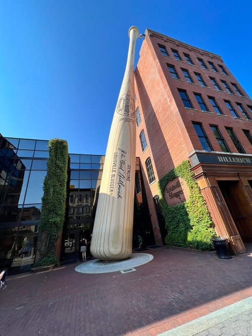 Giant baseball bat sculpture outside the Louisville Slugger Museum, with a clear blue sky in the background.