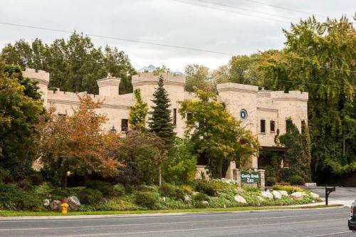 A stone castle-like building surrounded by trees and colorful flowers, with a sign reading "Castle Creek Inn."