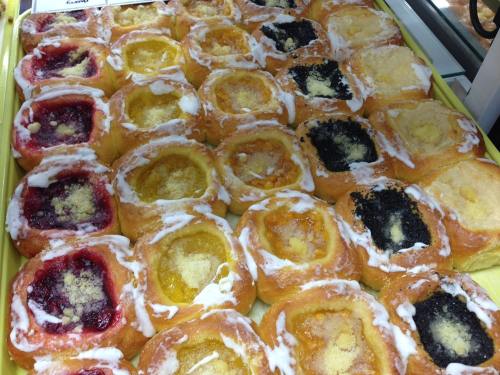 A tray of assorted pastries with colorful fruit fillings and icing, arranged in a grid pattern.
