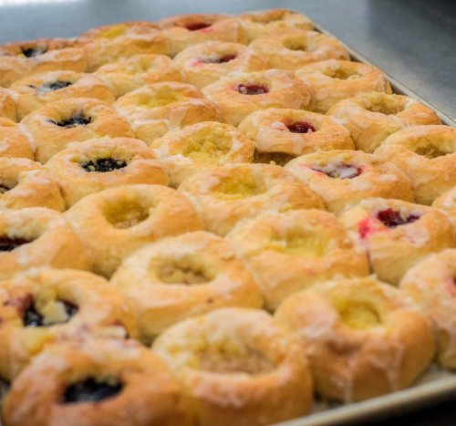 A tray of freshly baked pastries with various fruit fillings, arranged in a neat grid pattern.