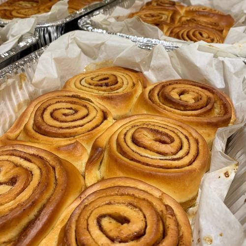 Freshly baked cinnamon rolls arranged in trays, showcasing their golden-brown swirls and soft texture.