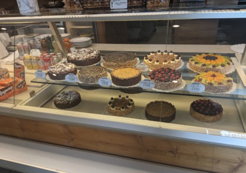 A display case filled with various cakes, including chocolate, fruit-topped, and layered desserts.