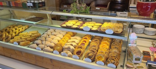 A display case filled with various baked goods, including pastries, rolls, and cookies, arranged neatly.