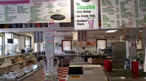 A colorful menu board in an ice cream shop, listing flavors and classic drinks, with a clean, inviting interior.