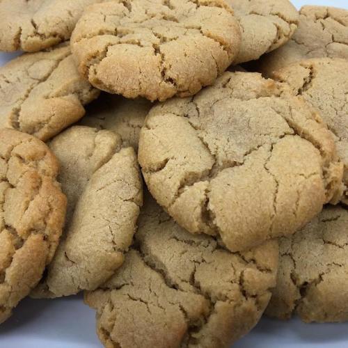 A close-up of a pile of freshly baked, golden-brown cookies with a cracked surface.