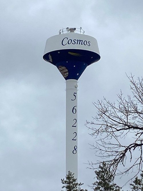 A tall water tower painted blue and white, labeled "Cosmos" with the number "56228" on its side, against a cloudy sky.
