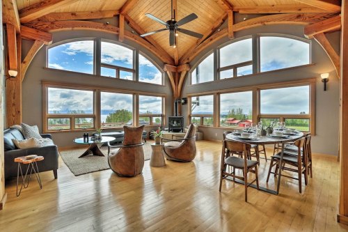 Spacious, modern living area with large windows, wooden beams, and a dining table overlooking scenic views.