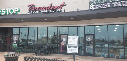 Exterior view of a coffee and dessert bar named "Decadent," with outdoor seating and nearby shops.