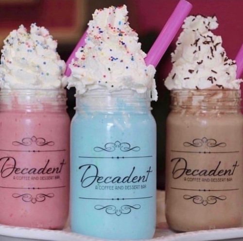 Three colorful milkshakes in jars topped with whipped cream, sprinkles, and straws, labeled "Decadent."