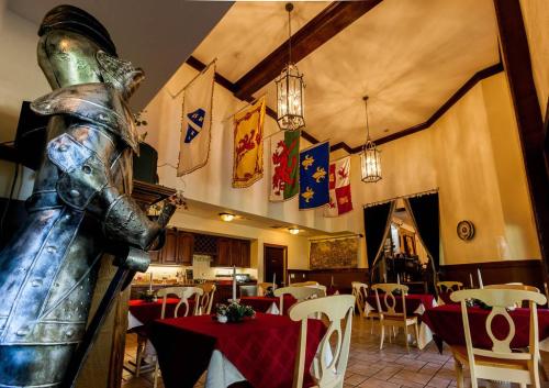 A dining area with red tablecloths, medieval banners hanging from the ceiling, and a knight statue in the foreground.