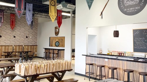 Interior of a distillery featuring wooden tables, a bar, and decorative banners on the walls.