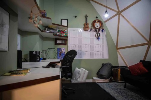 Cozy workspace with a desk, chair, calendar, and musical instruments in a uniquely shaped room.