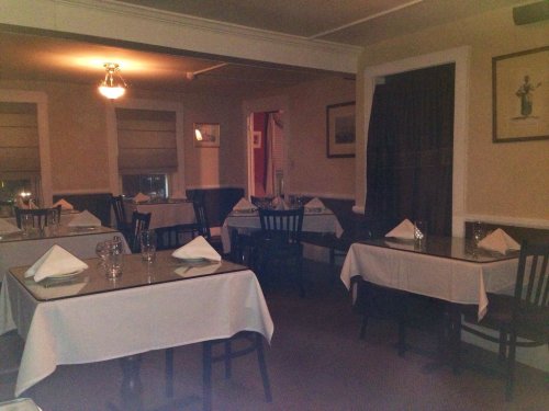 Cozy restaurant interior with empty tables set for dining, soft lighting, and a warm atmosphere.