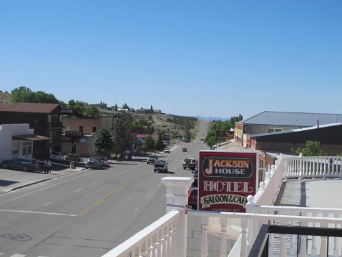 View of a street lined with buildings, featuring a sign for Jackson House Hotel and Saloon, under a clear blue sky.