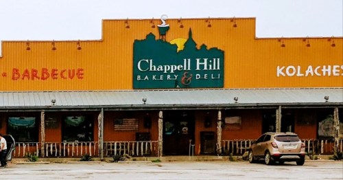 Exterior of Chappell Hill Bakery & Deli, featuring a colorful sign and a parked car in front.