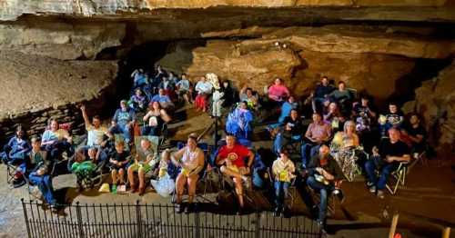 A group of people sitting in folding chairs inside a cave, enjoying an event together.