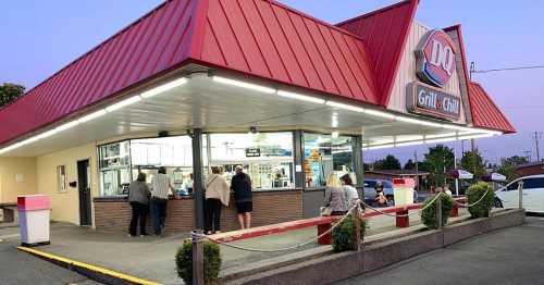 A Dairy Queen Grill & Chill restaurant at dusk, with customers ordering at the counter and a red roof overhead.