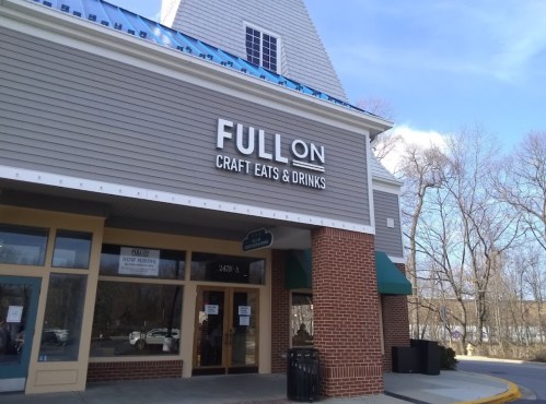 Exterior of a restaurant named "FULL ON Craft Eats & Drinks," featuring a welcoming entrance and clear blue sky.