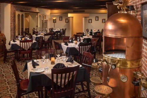 Elegant restaurant interior featuring wooden tables, chairs, and a vintage copper machine as a focal point.