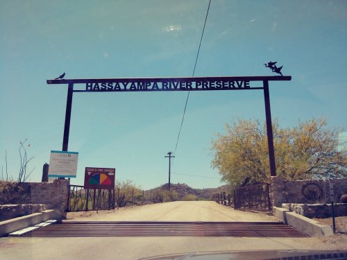 Entrance sign for Hassayampa River Preserve, featuring a metal arch and surrounding desert landscape.