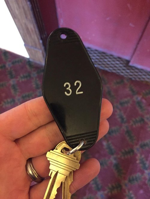 A hand holding a black keychain with the number 32, attached to a set of keys.