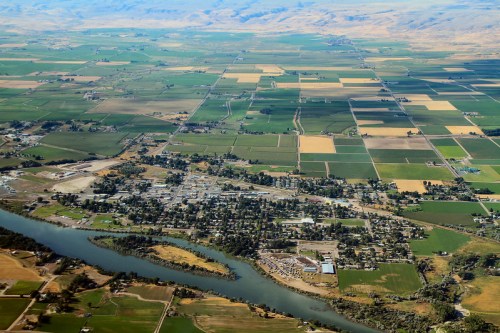 Aerial view of a rural landscape with fields, a river, and a small town surrounded by farmland.