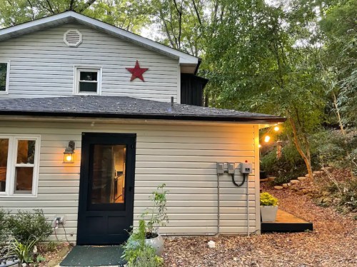 A cozy house exterior with a star decoration, surrounded by trees and warm outdoor lighting.