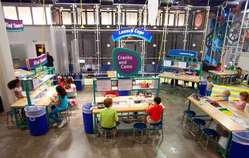 Children engage in hands-on activities at science stations in a colorful, interactive learning space.