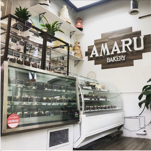 Interior of Amaru Bakery featuring display cases filled with desserts and a wooden sign on the wall.