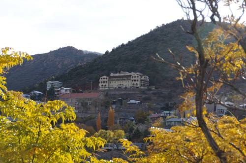 A hillside view of a large building surrounded by autumn foliage and mountains in the background.