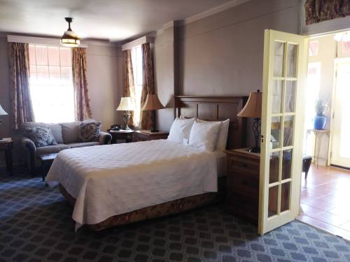 Cozy hotel room featuring a queen bed, seating area, lamps, and large windows with natural light.