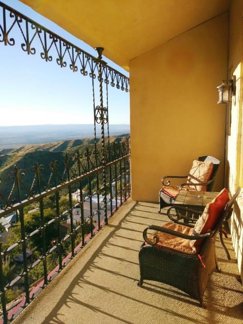 A sunny balcony with two chairs overlooking a scenic view of hills and a distant landscape.