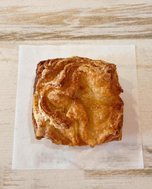 A golden-brown pastry with a flaky, twisted texture, resting on a white paper napkin.