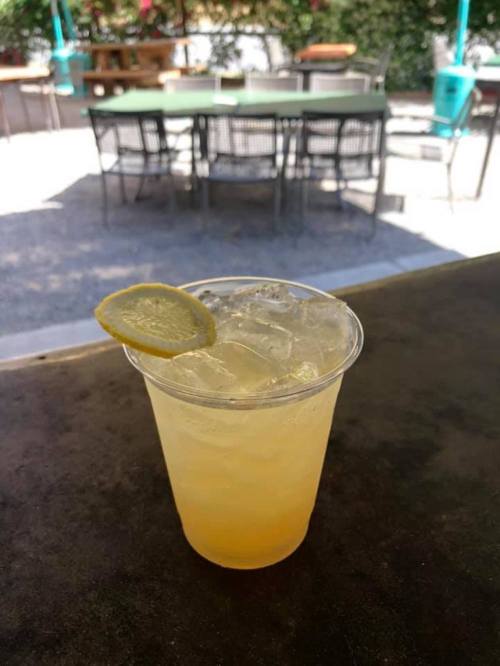 A refreshing drink with ice and a lime slice, set on a table in an outdoor café.