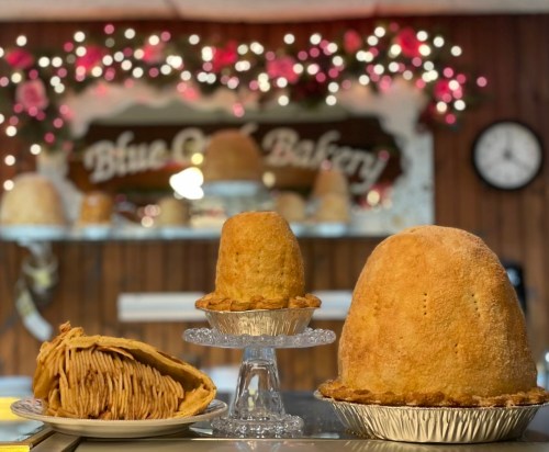 Three baked goods displayed on a counter, with a festive bakery backdrop featuring lights and decorations.