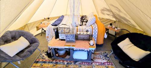 Cozy tent interior with a bed, decorative pillows, and seating, creating a warm, inviting atmosphere.