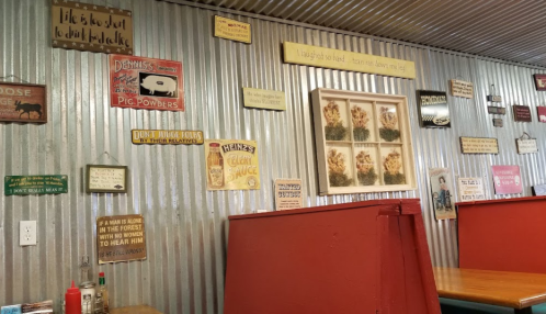 Interior of a rustic restaurant with metal walls, featuring various humorous signs and decorations.