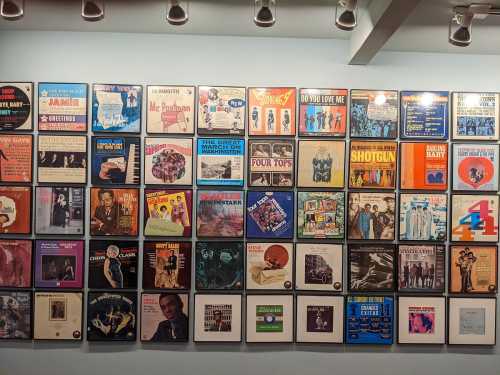 A wall display featuring various vintage album covers in a grid layout, showcasing diverse music genres and artists.