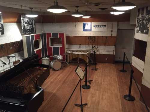 Interior of Motown Studio A featuring a grand piano, drums, and sound equipment, with vintage photos on the walls.