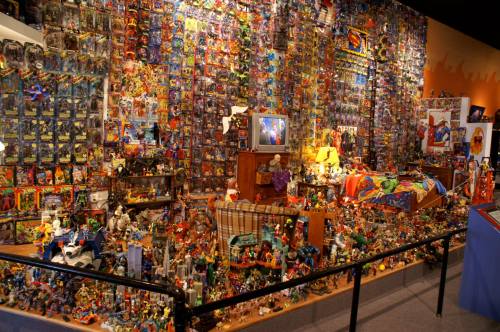 A vibrant display of action figures and collectibles covering walls and shelves in a colorful room.