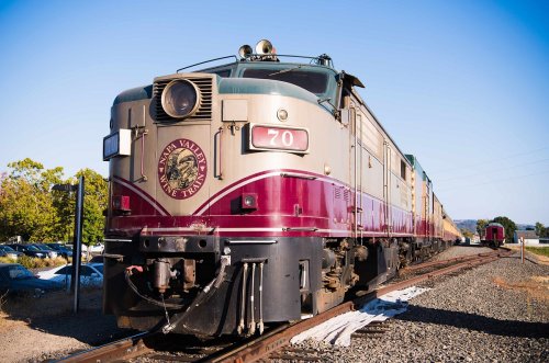 A vintage train engine numbered 70, parked on tracks with a clear blue sky in the background.