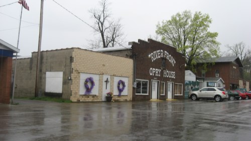 A rainy day view of the River Front Opry House, featuring purple wreaths on the doors and nearby buildings.