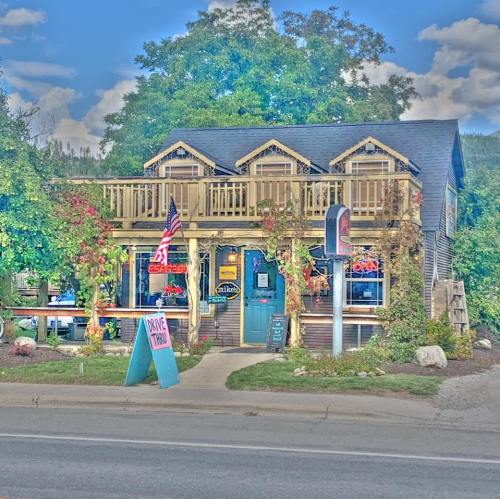 A charming two-story restaurant with a porch, surrounded by greenery and featuring an American flag and a drive-thru sign.