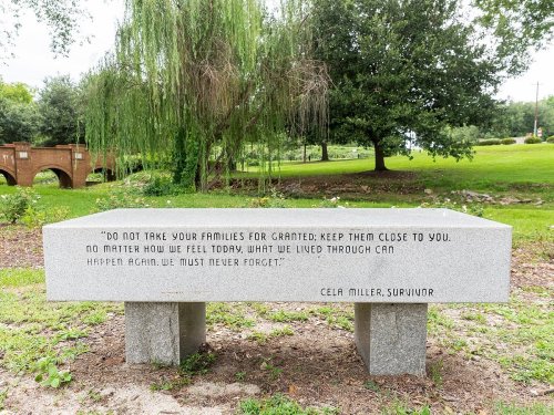 A stone bench with an inscription by Cela Miller, a survivor, urging to cherish families and remember past experiences.